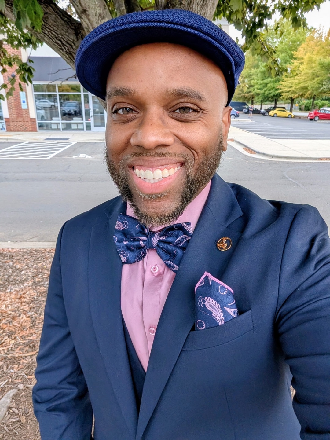 Miles in a navy suit with bow tie and flat cap, outdoors